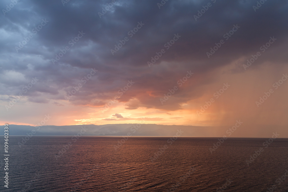 Rain storms are happening at sea in sunset time