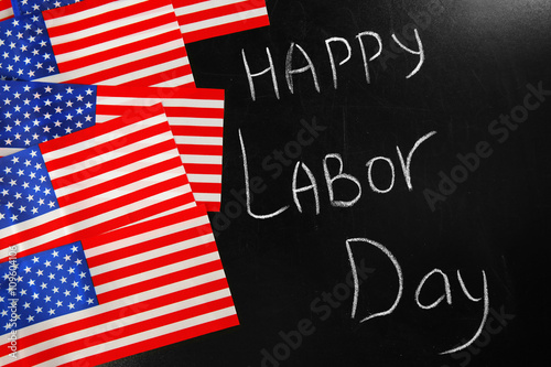 Happy Labour Day text and USA national flags on blackboard