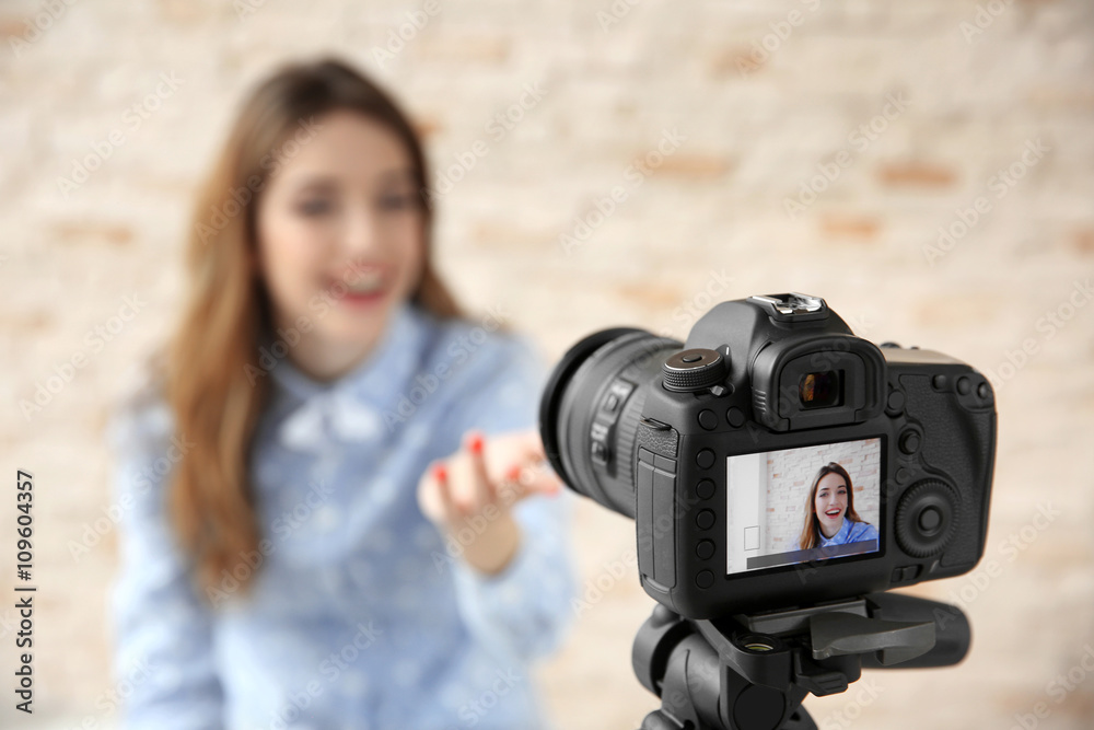 Naklejka premium Young female blogger with laptop on camera screen