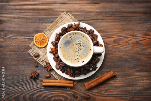 Cup of coffee with spices on wooden table, top view
