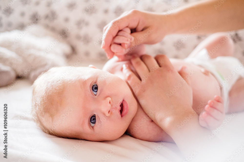 Baby boy lying on bed, held by his mother Baby boy lying on bed, held by his mother