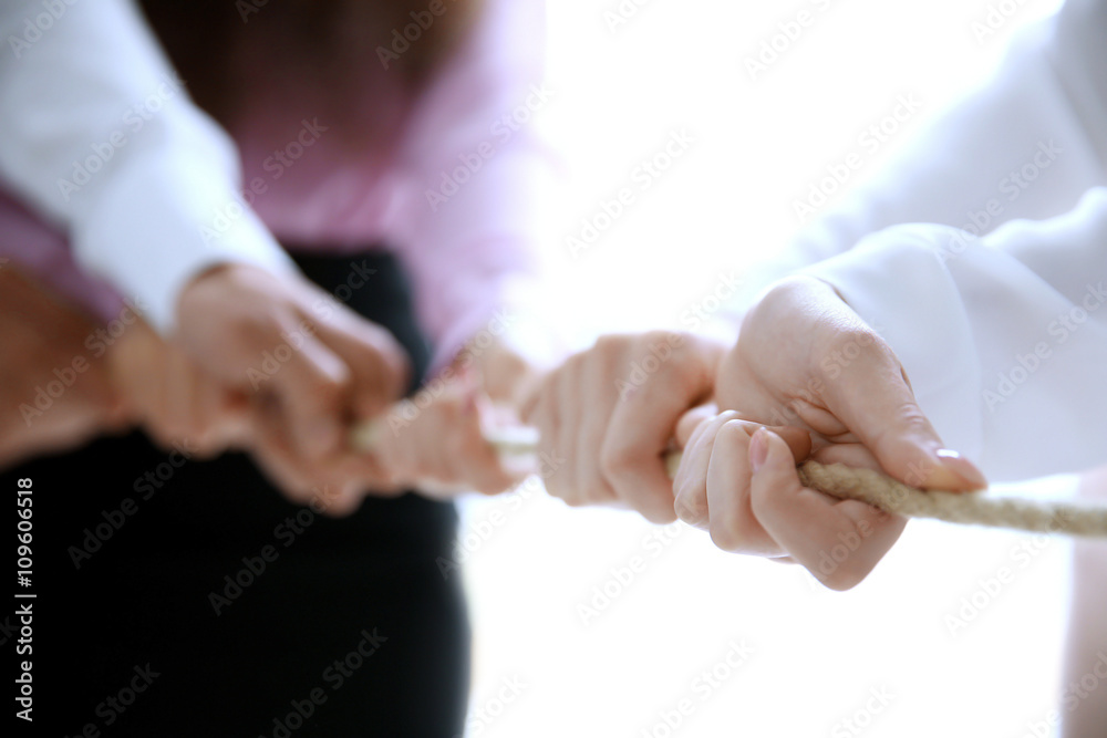 People hands pulling rope for playing tug of war closeup