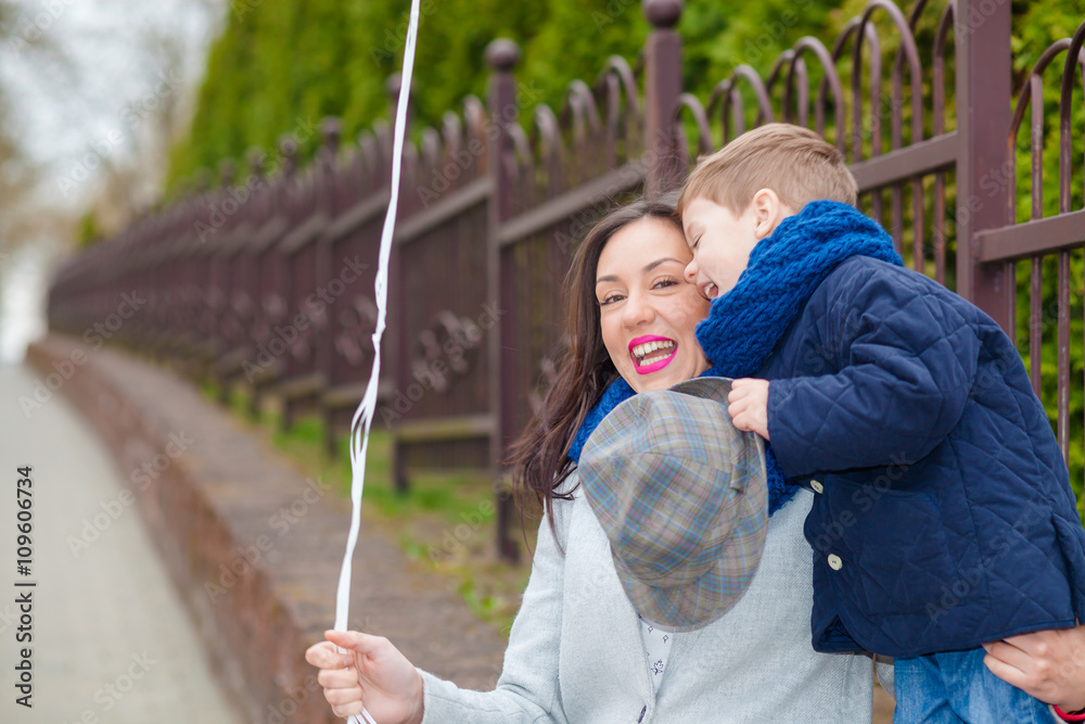 Obraz premium Portrait of fashionable baby boy and his gorgeous mother among balloons. little boy hugs his mother emotionally.