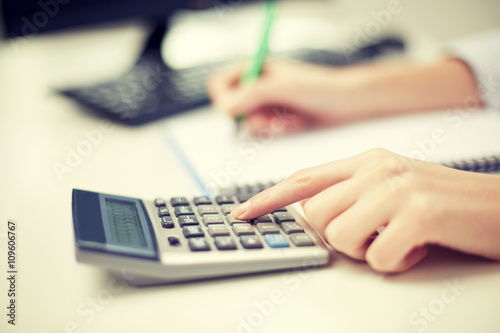 close up of woman with calculator taking notes