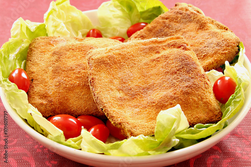 A dish with baked mozzarella in carrozza with green salad and tomatoes cherry. Red background. photo
