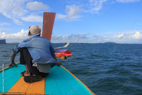 fisherman sit on nose of long tail boat in a sea to think about desination way