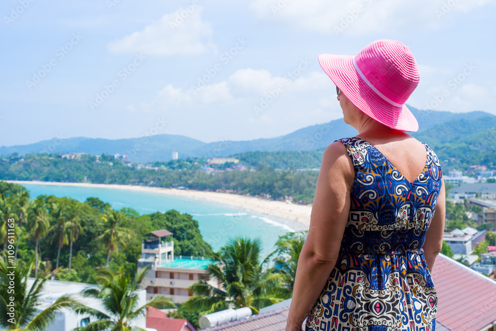 Middle-aged woman enjoying the view over Kata beach from the hotel balcony. Phuket, Thailand.