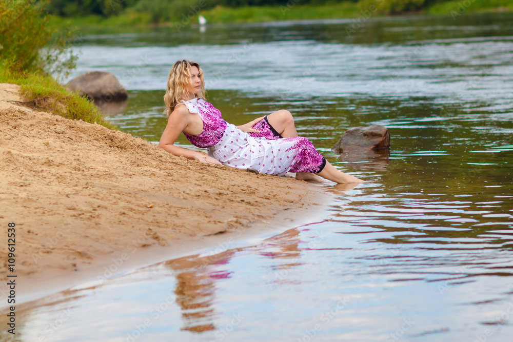 Fototapeta premium Woman in a long dress on the shore near the water
