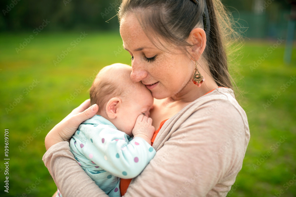 Mother holding her baby daughter, outside in spring nature Mother holding her baby daughter, outside in spring nature