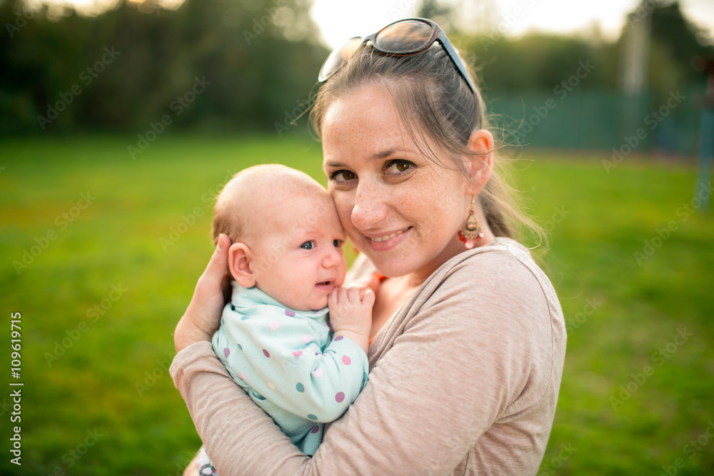 Mother holding her baby daughter, outside in spring nature Mother holding her baby daughter, outside in spring nature