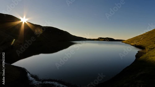 Time lapse of sun setting over a mountain at the sunset at scaffaiolo lake italy backlit sunrays photo