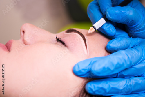 close up of beautician preparing young woman for permanent eyebr