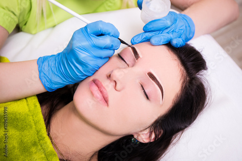 permanent eyebrow make up - beautician applying anesthesia and p photo