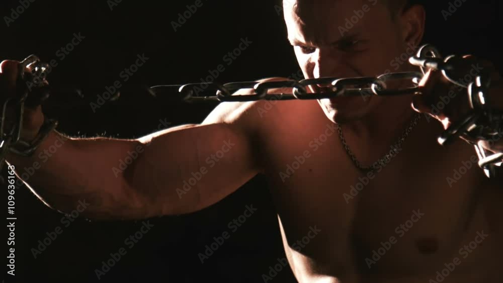 Topless muscular man trying to thorn iron chain