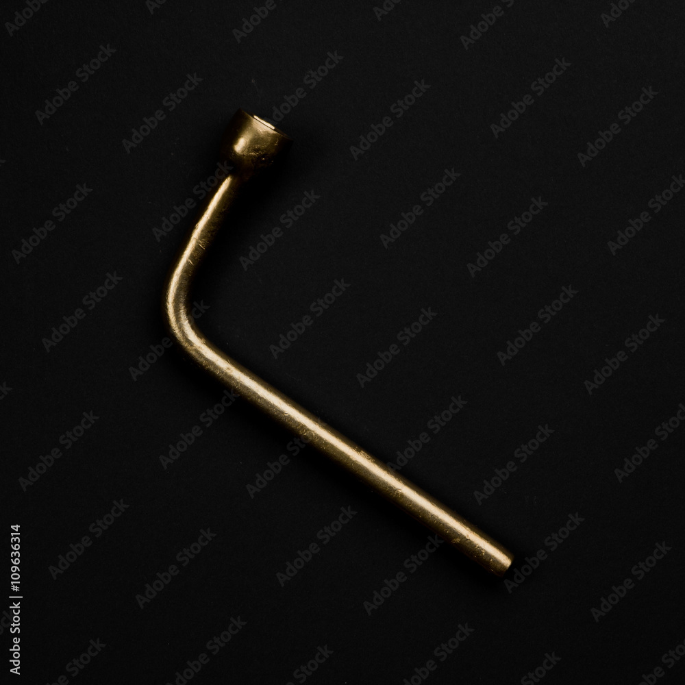 Golden wheel wrench isolated on black background. Symbolic car r Golden wheel wrench isolated on black background. Symbolic car r