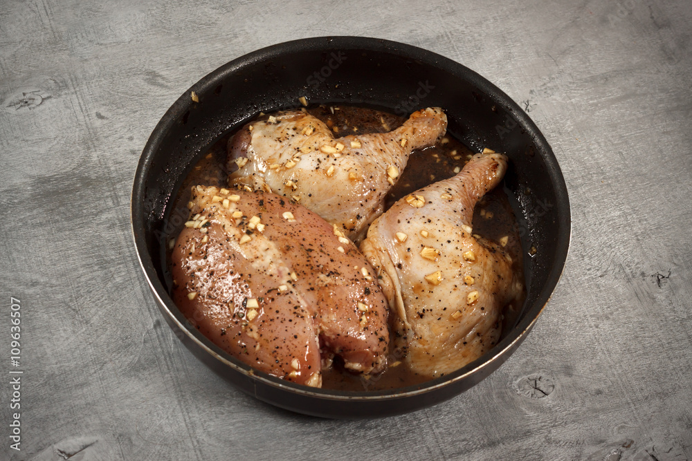 Raw chicken meat in marinade in frying pan ready for cooking Raw chicken meat in marinade in frying pan ready for cooking