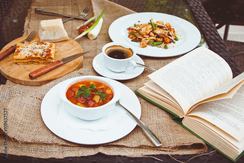 Business lunch with soup, salad and coffee served at the table in the restaurant. On the cloth lay the glasses and the book