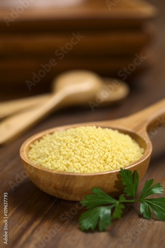 Raw couscous on wooden spoon with parsley leaf on the side (Very Shallow Depth of Field, Focus one third into the couscous) photo