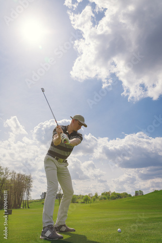 Male golf player hitting from fairway on golf course at sunny day