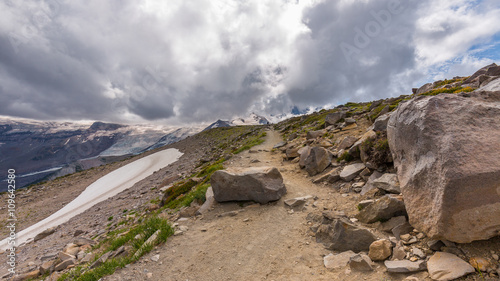 Rocky slopes in the mountains. Amazing view at the peaks which rose against the cloud sky. Path on the tops of mountains. BURROUGHS MOUNTAIN TRAIL, Sunrise Area, Mount Rainier National Park photo