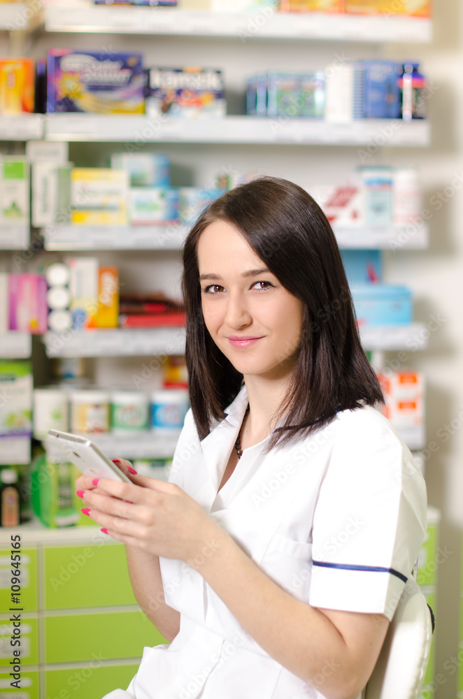 Young pharmacist woman using a app on a smart phone Pharmaceutical background. Drugstore. Pills and medicine. 