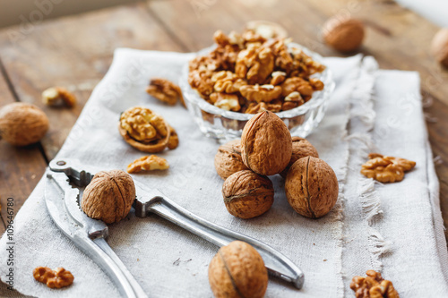 Glass bowl with walnuts on rustic homespun napkin. Healthy snack on old wooden background.