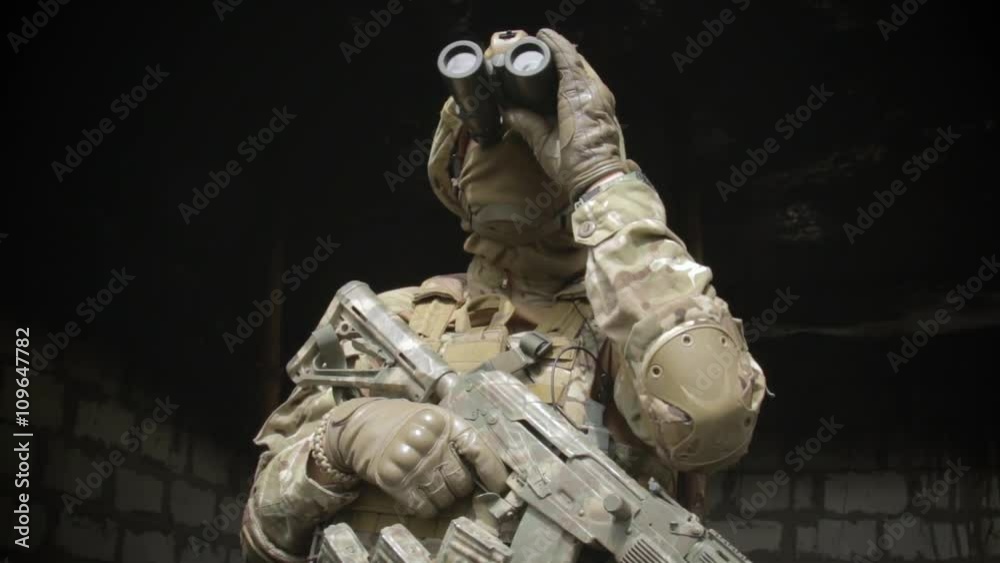 Soldier in the burned a room aiming a machine gun and looking through ...