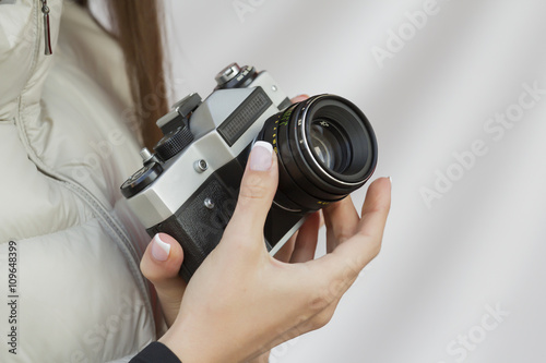 girl with French manicure holds in hand vintage camera