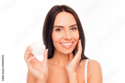 Portrait of pretty woman holding jar and applying cream on her