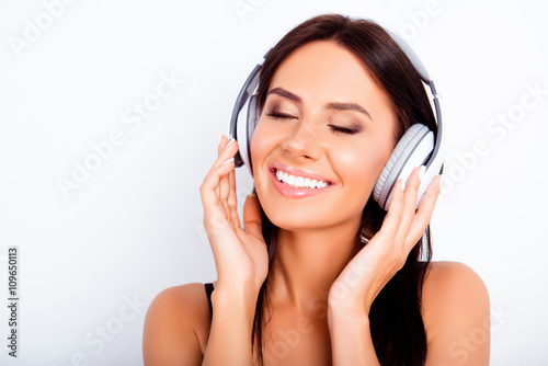 Pretty young woman listening music in headphones with closed eye