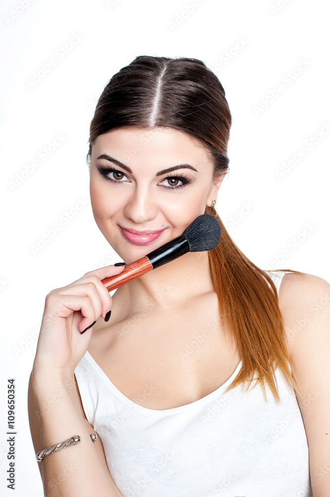 Obraz premium Beauty Girl make up artist with Makeup Brush. Bright Holiday Make-up for Brunette Woman with Brown Eyes. Beautiful Face. Makeover. Perfect Skin. Applying Makeup