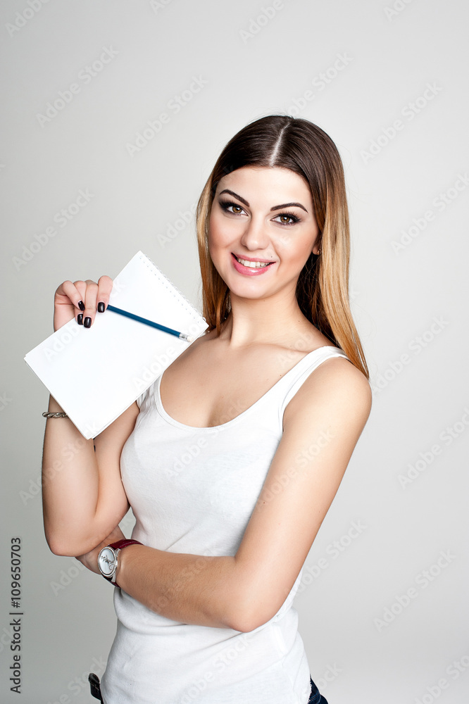 young positive smiling student girl with notebook and pen planning her daily schedule wearing casual white t-shirt on white. Studio retouched shot young positive smiling student girl with notebook and pen planning her daily schedule wearing casual white t-shirt on white. Studio retouched shot