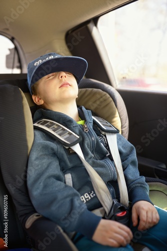 Cute little child sitting in safety car seat and sleeps