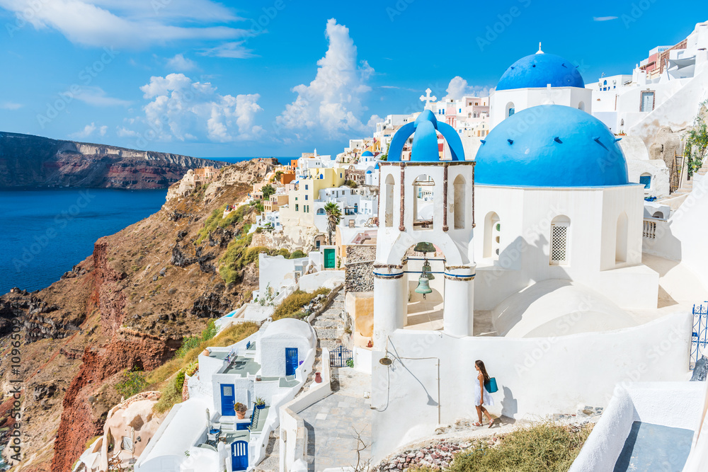 Fototapeta Europa, wyspy greckie, Grecja, Santorini miejsce wypoczynku turystycznego: Miasto Oia. Kobieta na wakacjach chodzi na schodach odwiedza sławną białą wioskę morzem śródziemnomorskim i błękitnymi kopułami.
