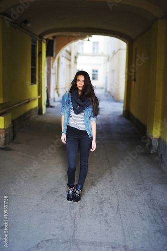 Free Download girl in a denim jacket and boots standing in the courtyards in the inner city under the arch - GFXLoad