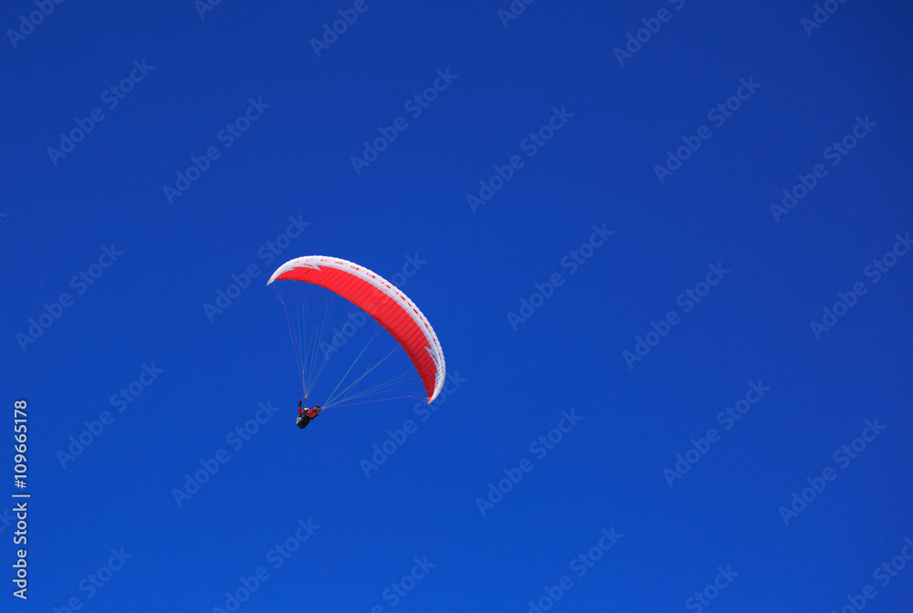 Paraglider with red parapent in a clear, blue sky. Paraglider with red parapent in a clear, blue sky.
