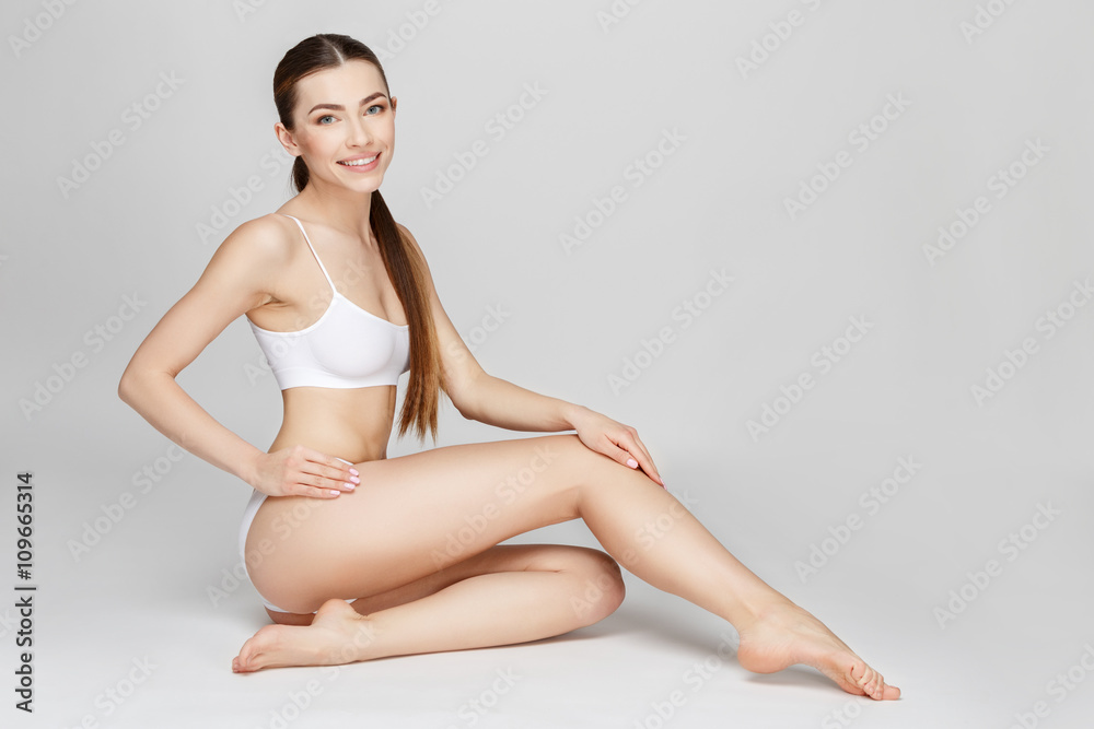 Fototapeta premium Slim tanned woman's body over gray background