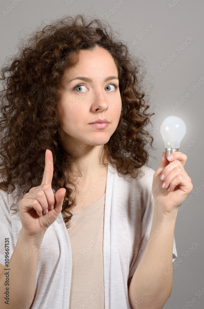 Beautiful business woman with idea light bulb on grey Beautiful business woman with idea light bulb on grey