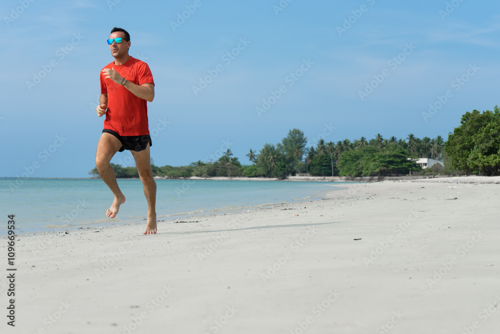 The man runs, runs on the beach, in the tropical country plays sports, with attached running a parachute behind the back