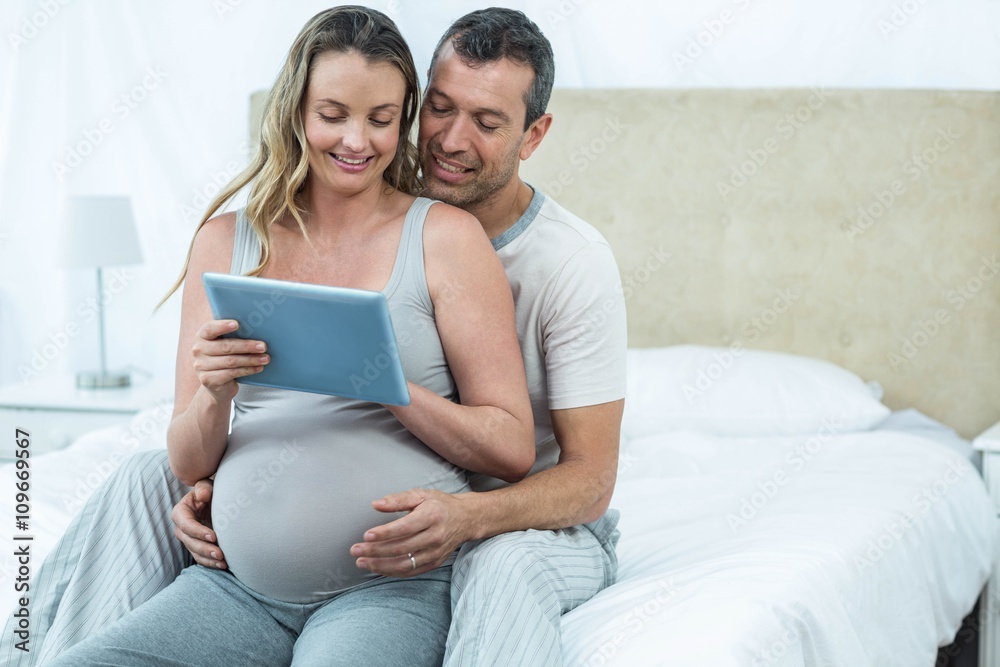 Expecting couple sitting on bed Expecting couple sitting on bed