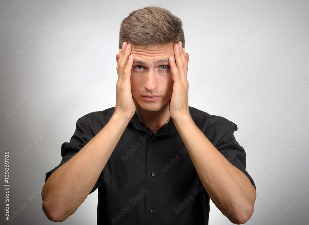 The man really tired, he holds his head with his hands. Gray background The man really tired, he holds his head with his hands. Gray background