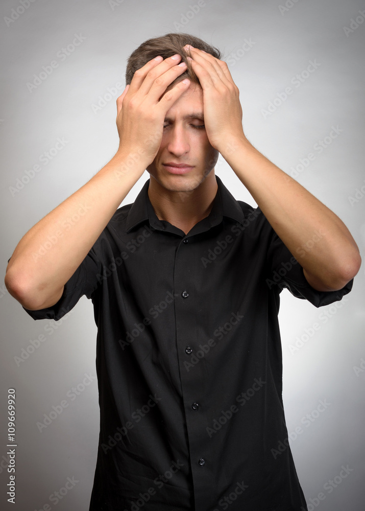 The man really tired, he holds his head with his hands. Gray background The man really tired, he holds his head with his hands. Gray background