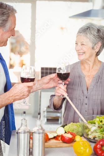 Happy senior man offering red wine to wife