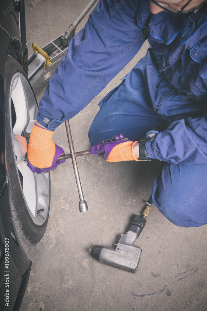 Car mechanic repairing tire in the service-shop.