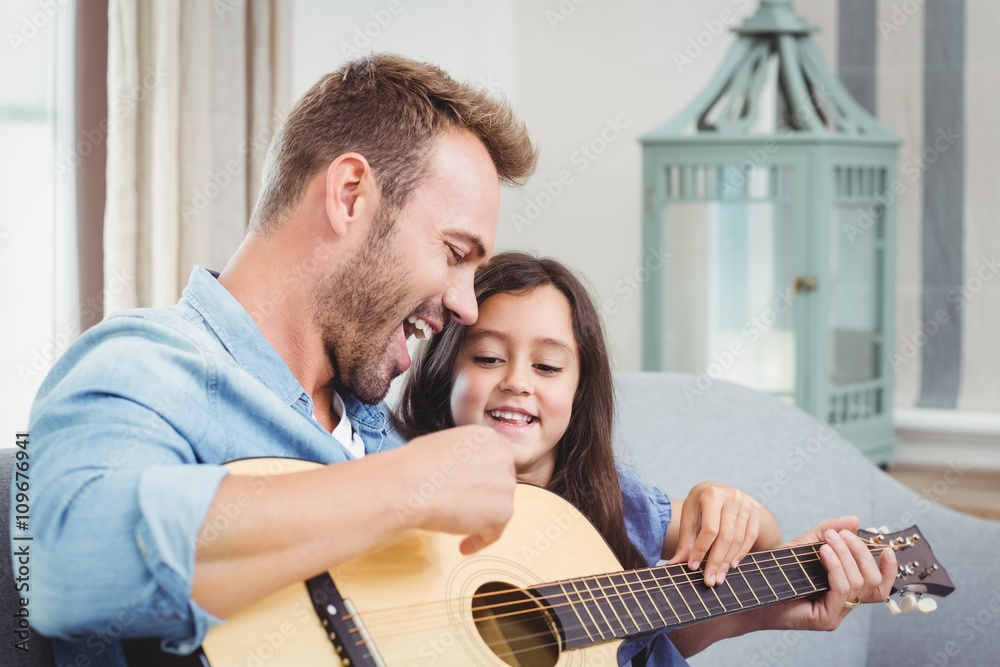 Fototapeta premium Father playing guitar with daughter