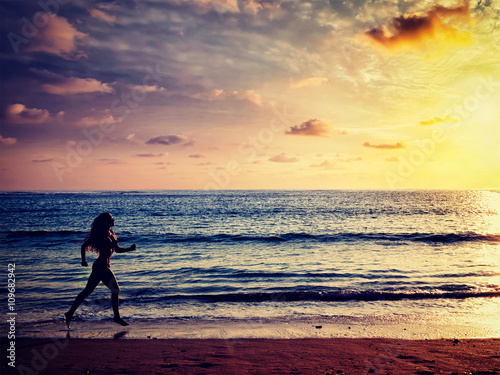 Fototapeta Naklejka Na Ścianę i Meble -  Beautiful athletic woman running along sea on the beach