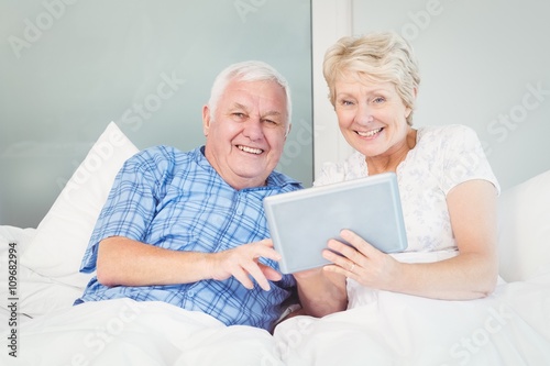 Portrait of senior couple using tablet on bed