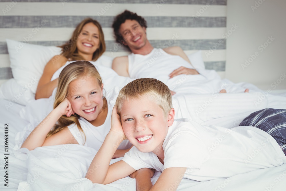 Portrait of happy family resting on bed