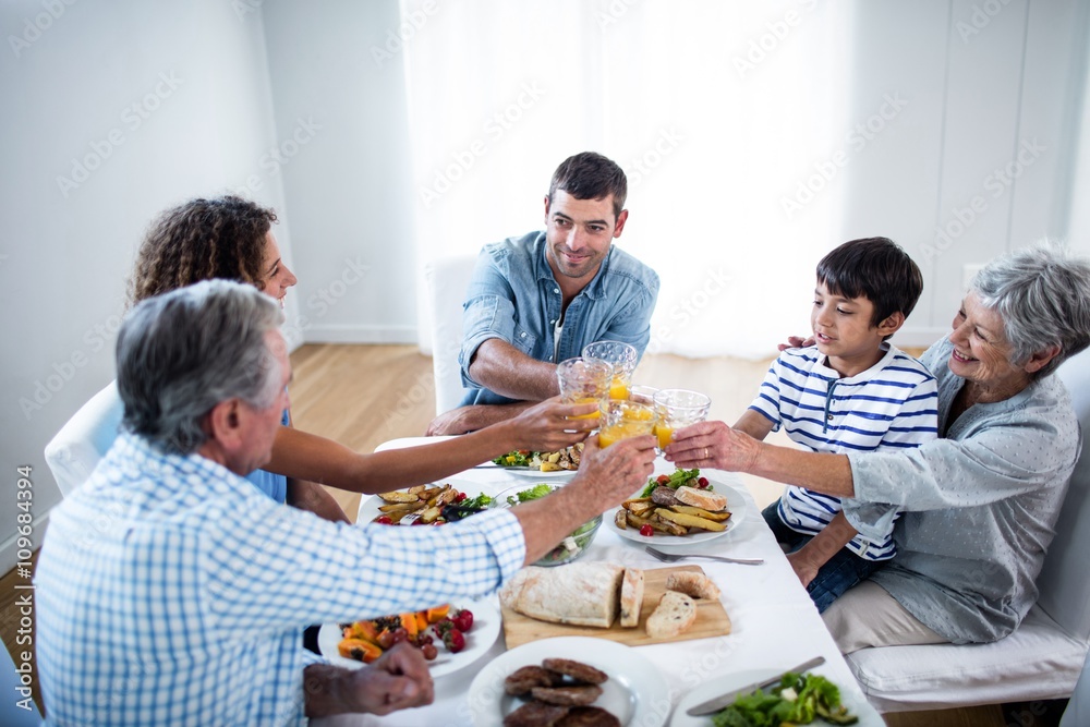 Family toasting glasses of orange juice while having breakfast