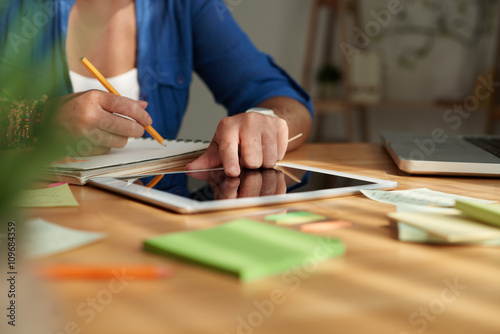 Woman using tablet computer and taking notes